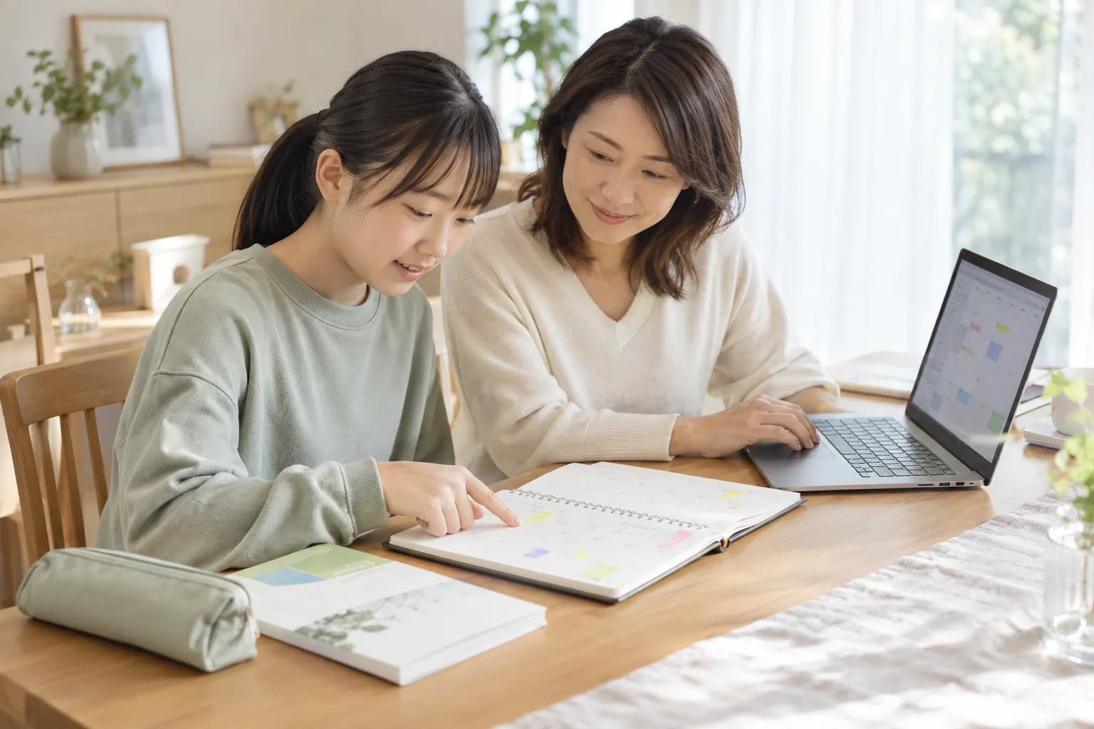 手帳とパソコンのカレンダーを見ながら、受験や勉強の予定を整理する親子